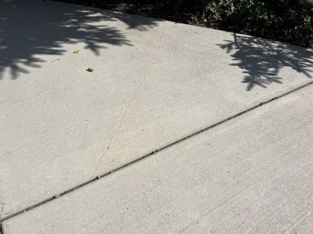 non-structural hairline crack in concrete sidewalk surface