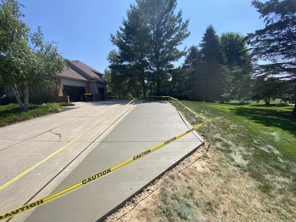 new concrete installation in a residential driveway surrounded by caution tape to protect curing slab
