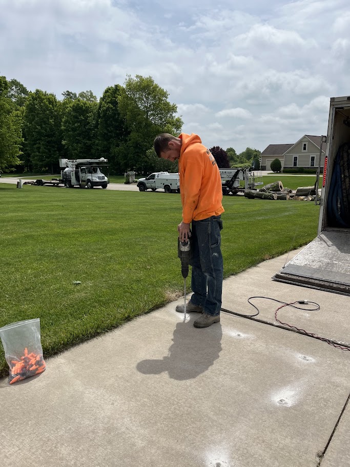 technician drilling small holes in uneven concrete driveway for polyurethane foam repair