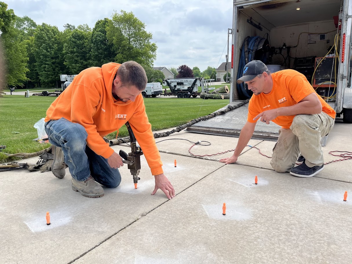 technician drilling small holes in uneven concrete driveway for polyurethane foam repair