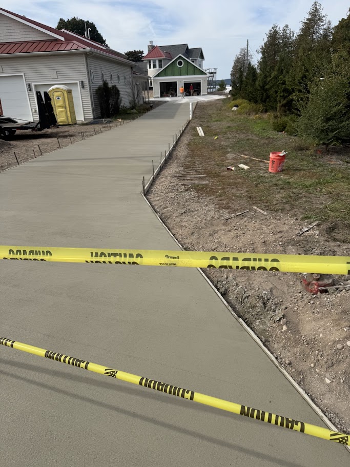 Freshly poured concrete driveway with caution tape at a northern Michigan cottage