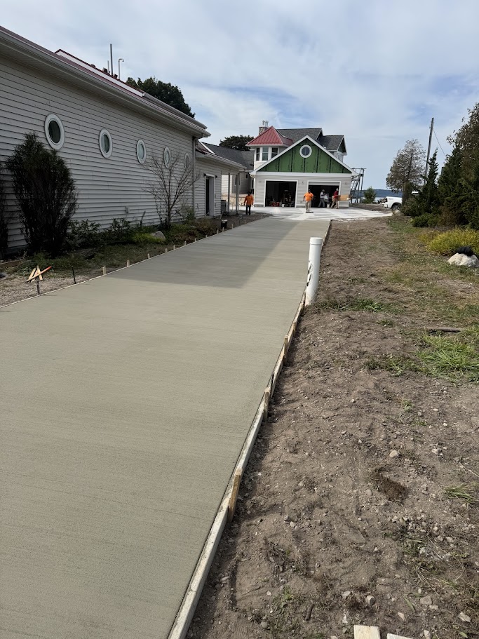 Long concrete driveway installation leading to a lakeside cottage in Beulah, Michigan