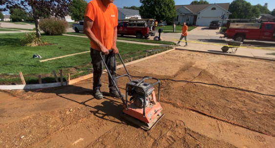 Compacting driveway base material before concrete placement