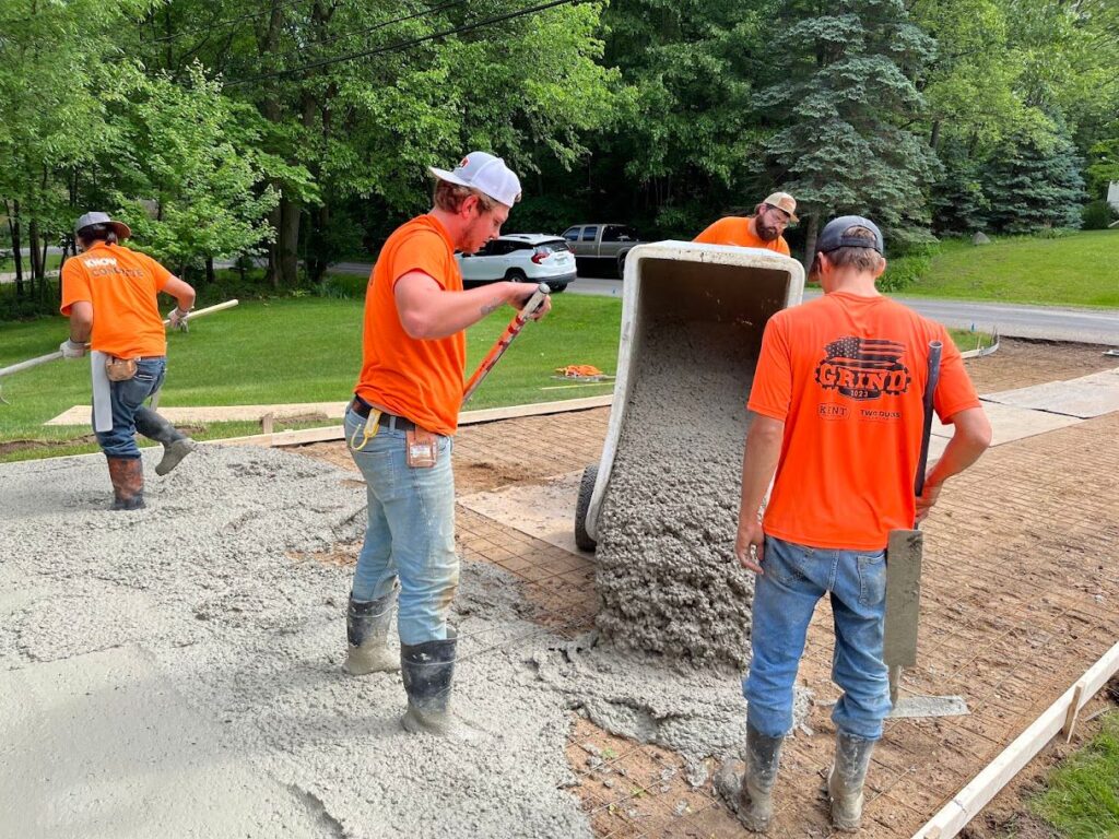 Fresh concrete being poured onto a prepared driveway base during installation